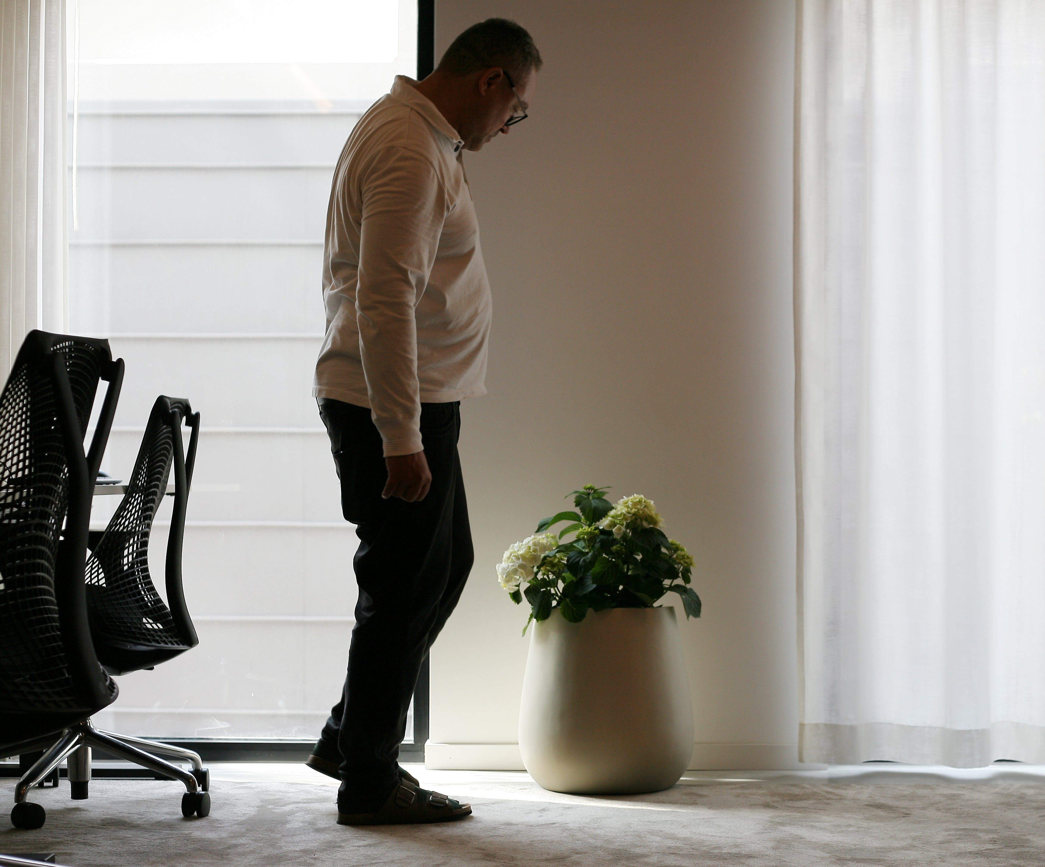 Man looking down on a okanter with flowers inside he office